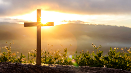 Cross on a hill, sunlight in background shining on the cross
